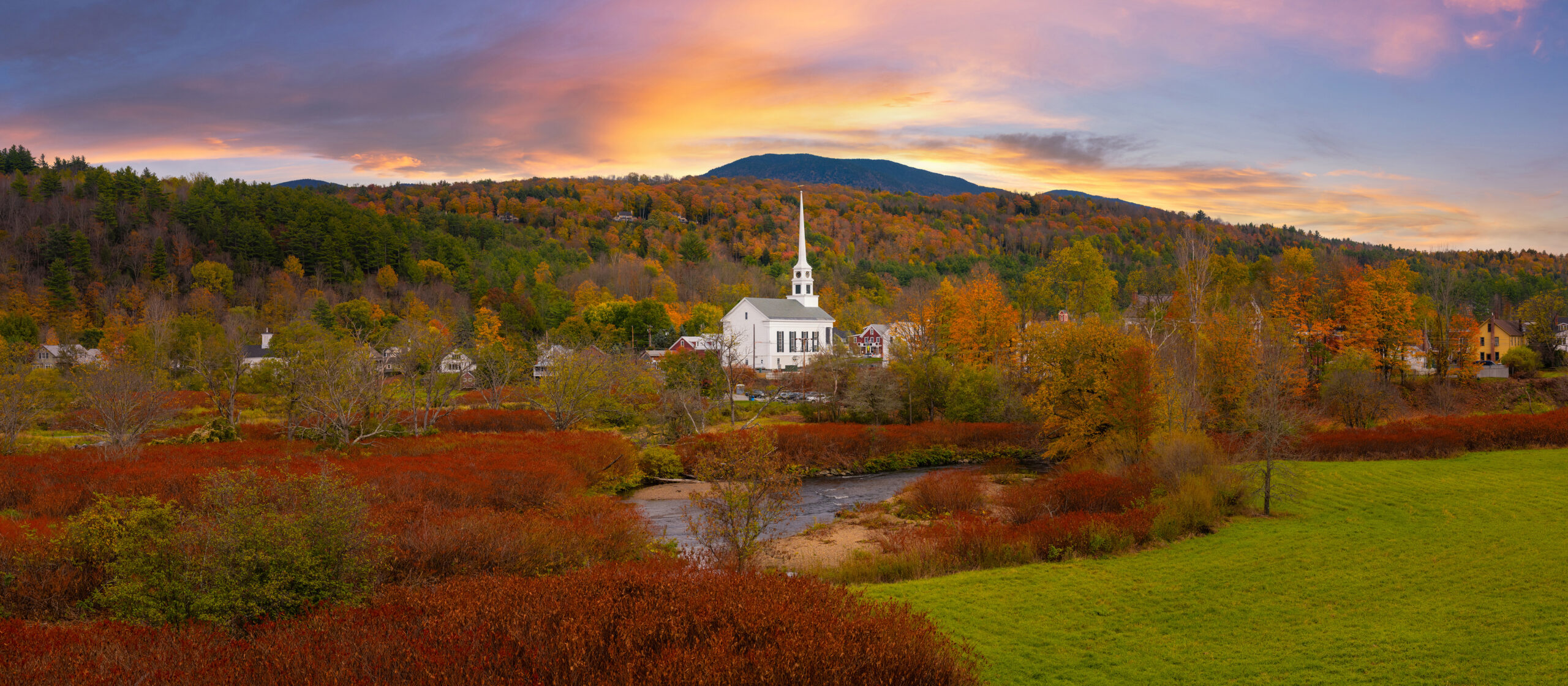panorama of stowe church in vermont surrounded by the beautiful fall foliage